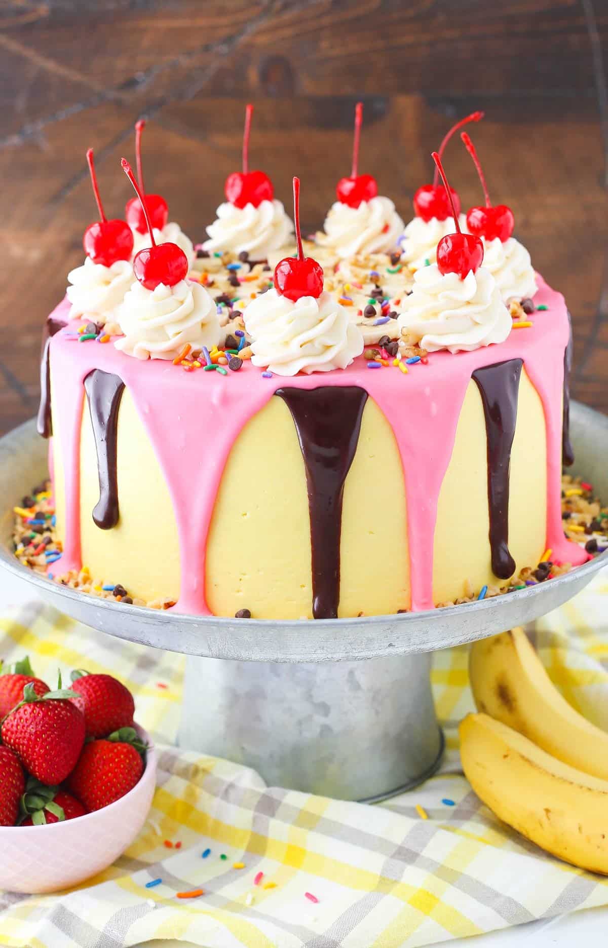 A banana split layer cake on a silver cake stand.
