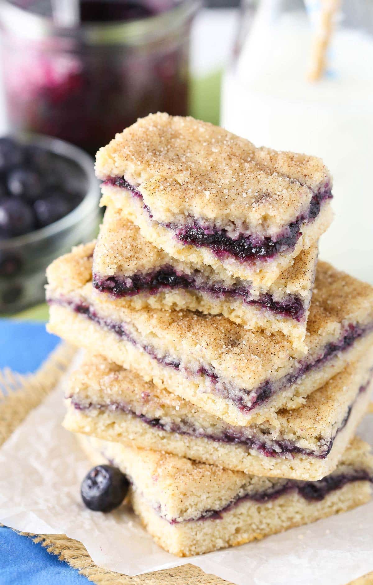 Close up of a stack of blueberry jam cake bars with the top bar broken to show filling.