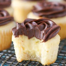 A Boston cream pie cupcake with a bite out of it to show center.