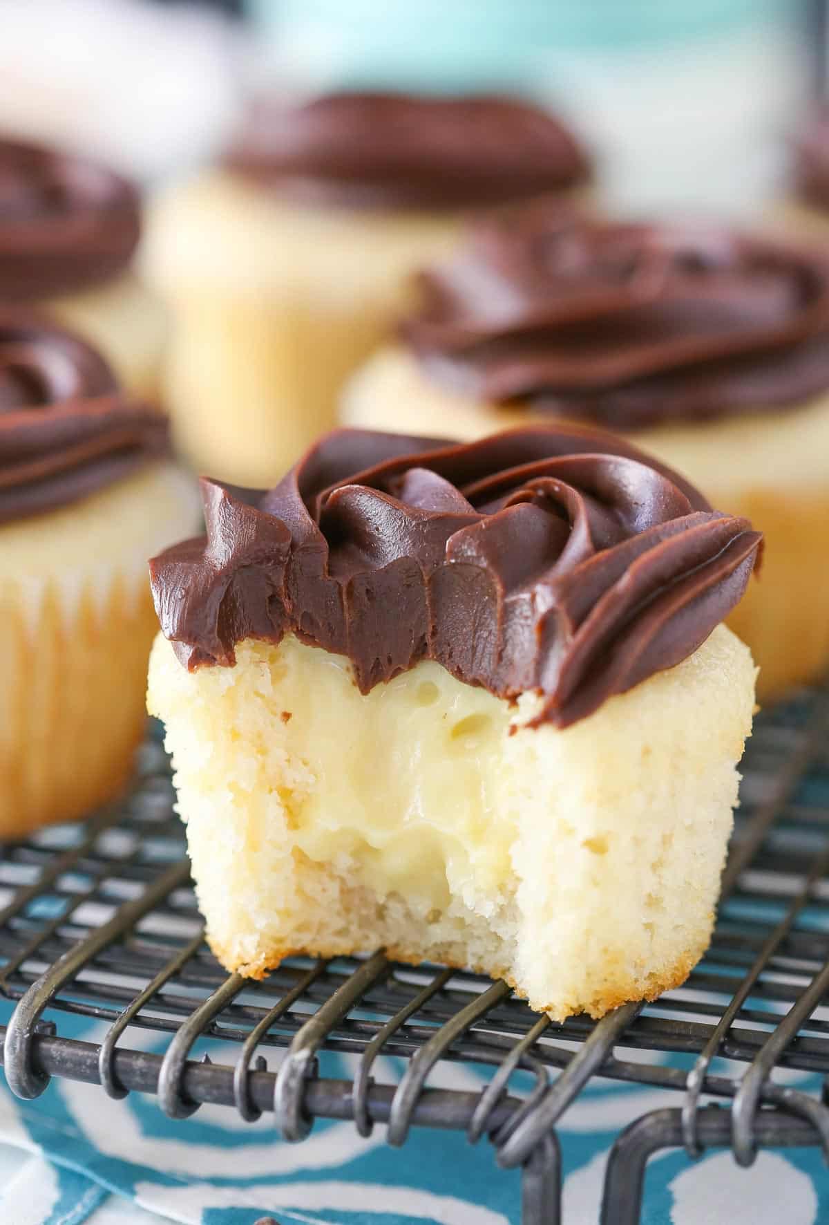 A Boston cream pie cupcake with a bite out of it to show center.