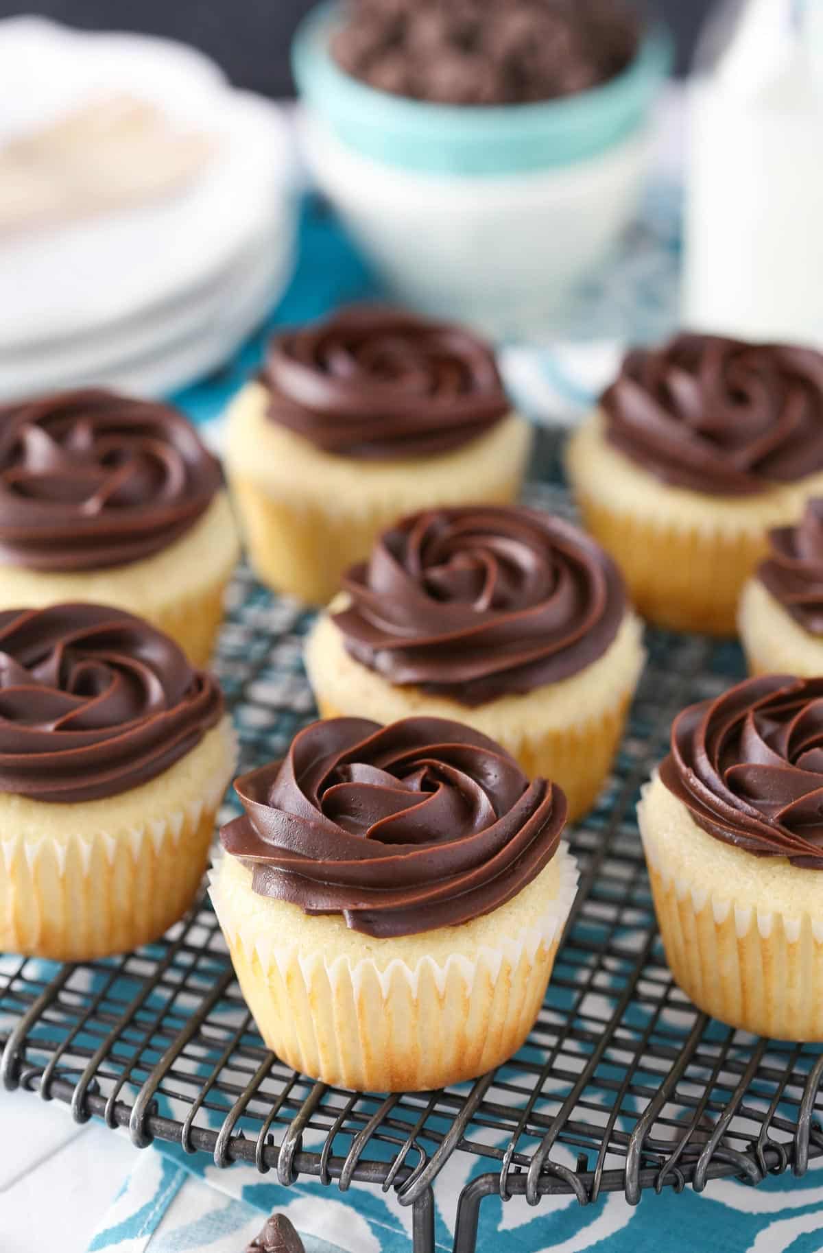Several Boston cream pie cupcakes on a wire rack.
