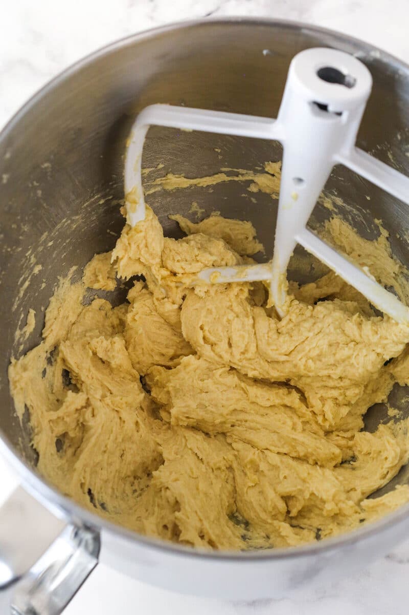 Mixing an egg and vanilla into creamed butter and sugar for cookie dough.