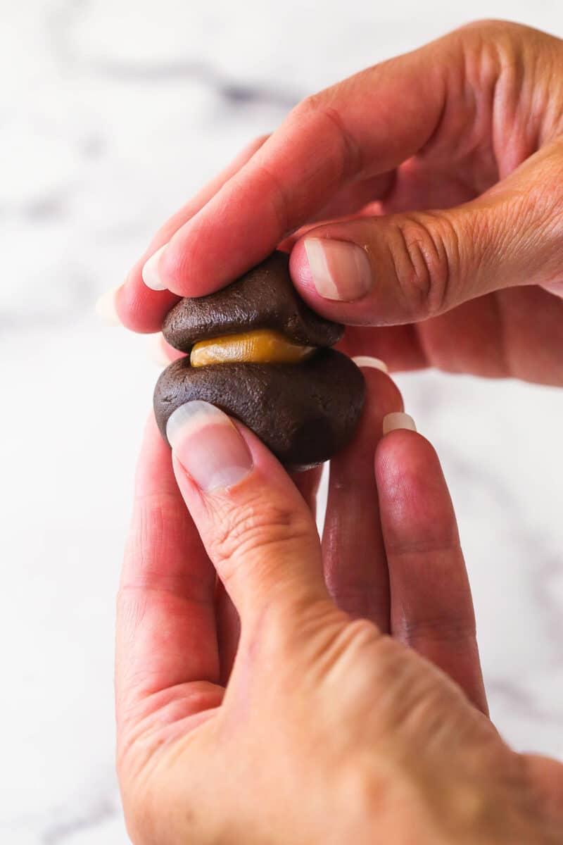 Sandwiching a caramel candy between two portions of chocolate cookie dough.