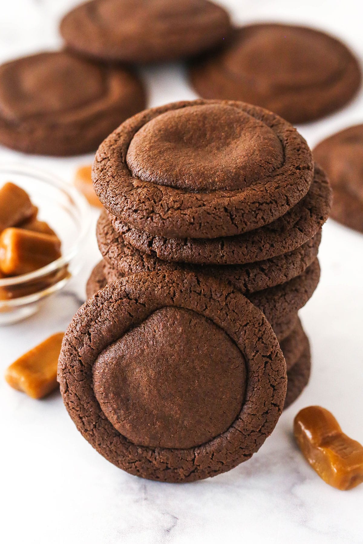 These caramel stuffed cookies feature a soft, chewy chocolate cookie dough that perfectly complements a gooey, sweet caramel center. A stack of caramel stuffed cookies.