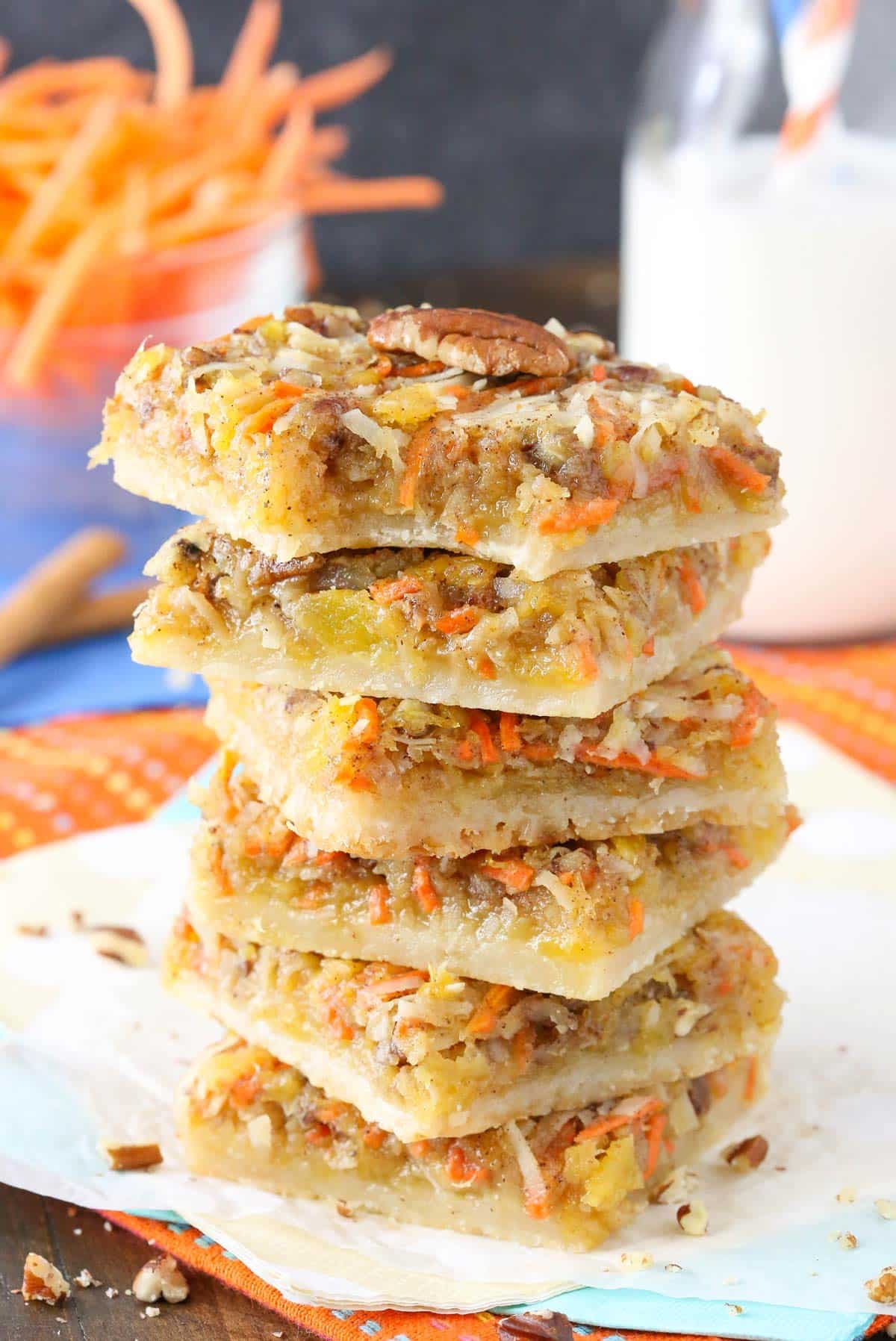 Six carrot cake shortbread bars stacked one on top of the other with a bite taken out of the top bar.