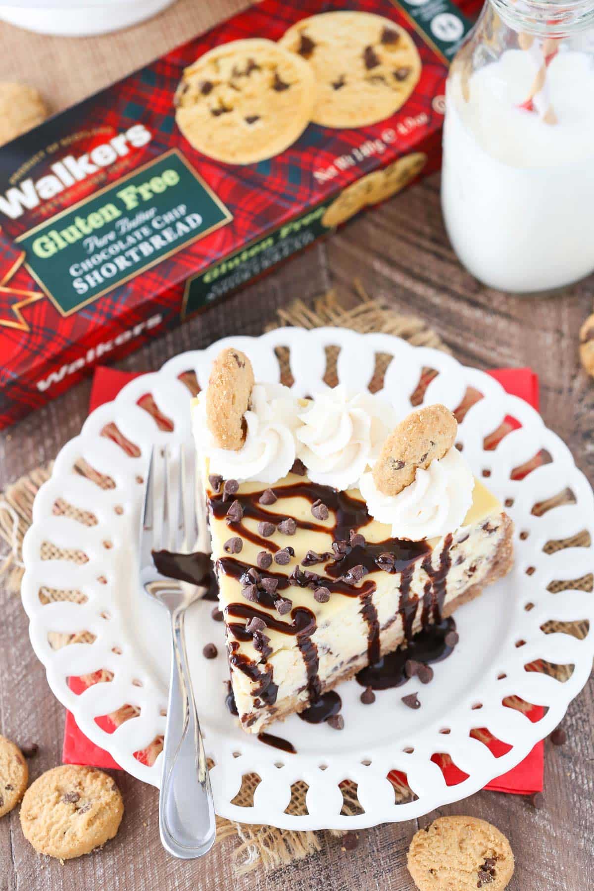 Top view of a slice of chocolate chip shortbread cheesecake drizzled with chocolate sauce on a small white plate.