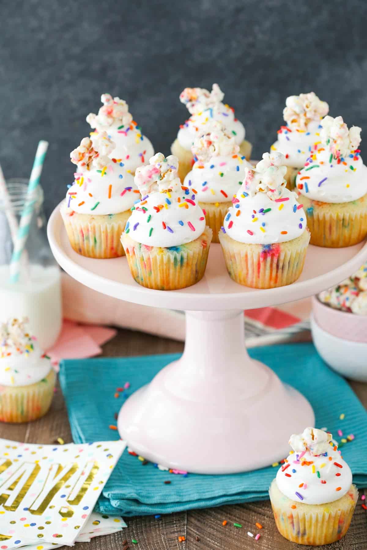 Close up of a light pink cake stand topped with several funfetti popcorn marshmallow treat cupcakes.