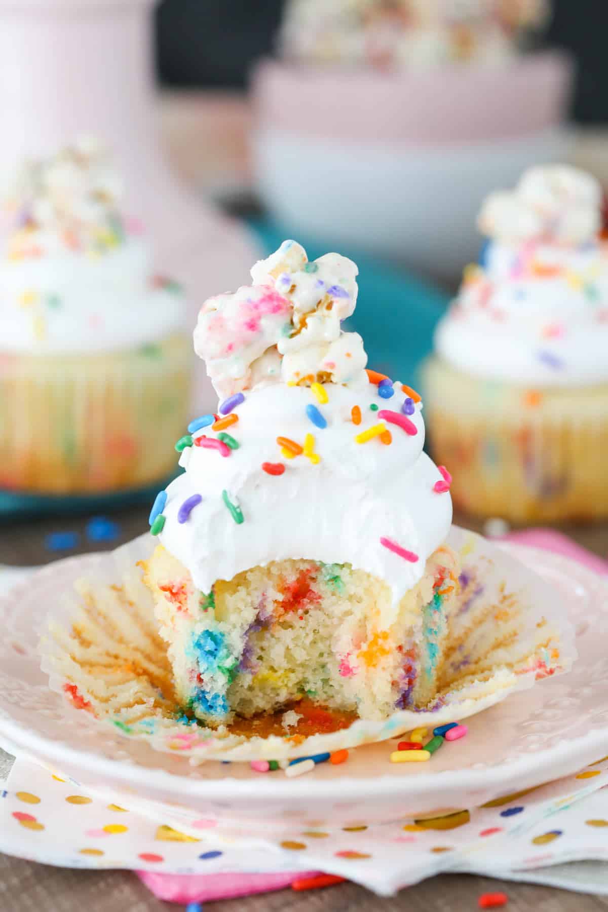 Close up of a funfetti popcorn marshmallow treat cupcake with a bite out of it.