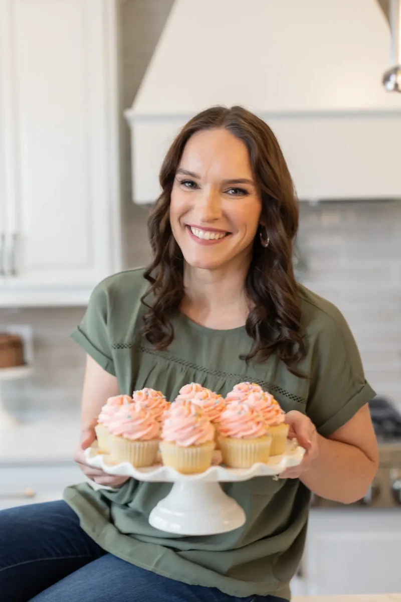 Lindsay, author of Life Love and Sugar, holding a plate of cupcakes and smiling.