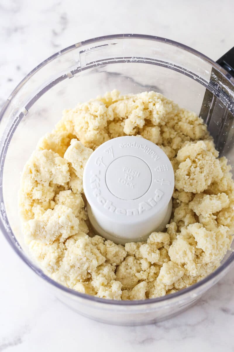 Flour, salt, and butter coming together in a food processor.