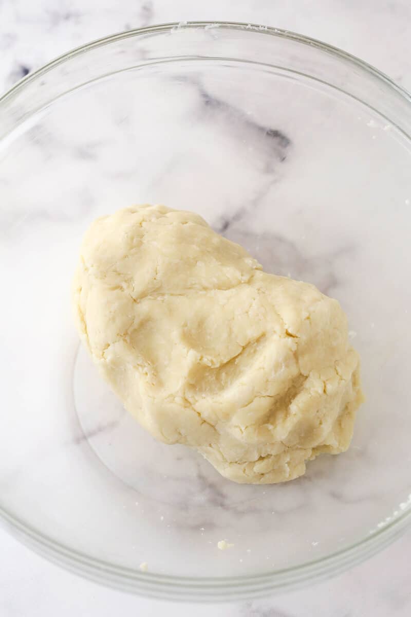 Pie dough coming together in a bowl.
