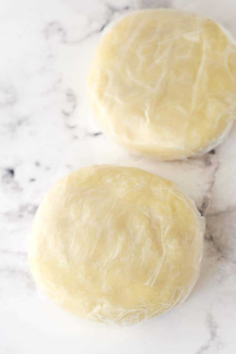 Pie dough formed into two disks and wrapped in plastic wrap.