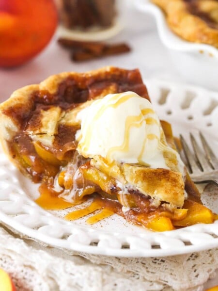 A slice of peach pie topped with vanilla ice cream.