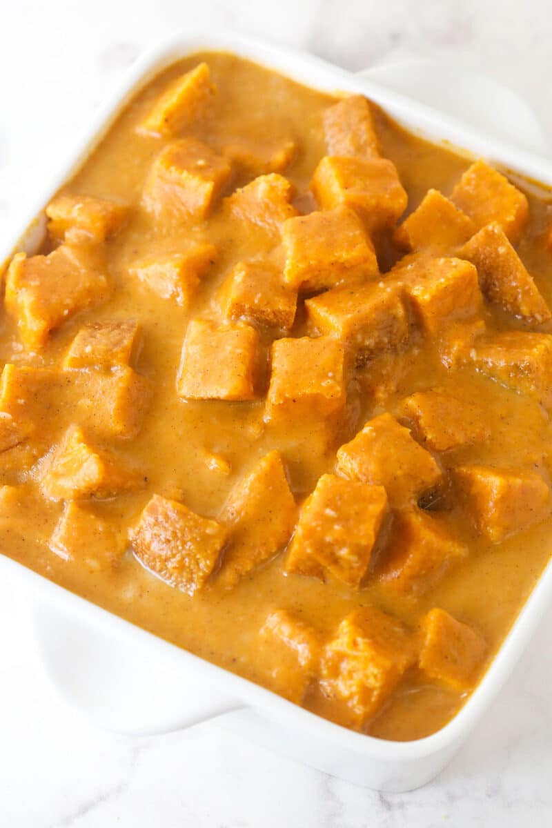 Bread cubes in pumpkin custard in a casserole dish.