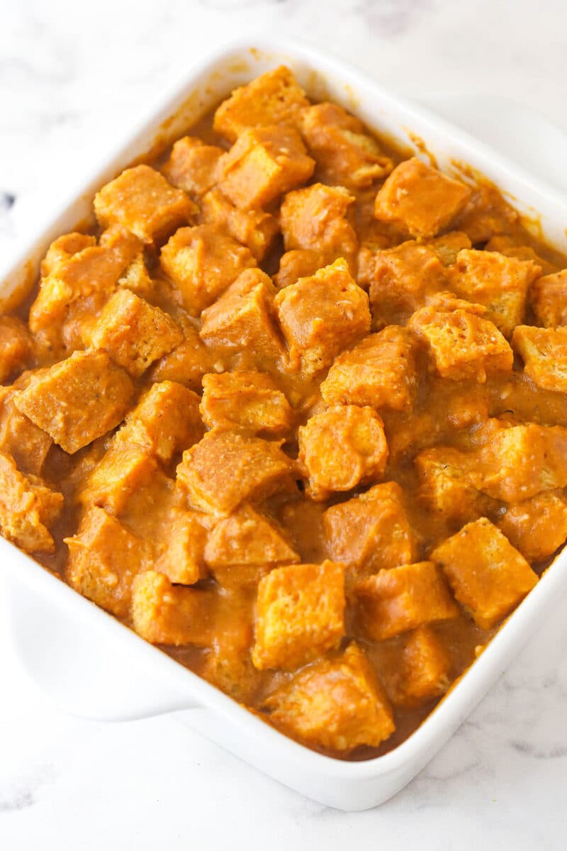Bread cubes soaked in pumpkin custard in a casserole dish.