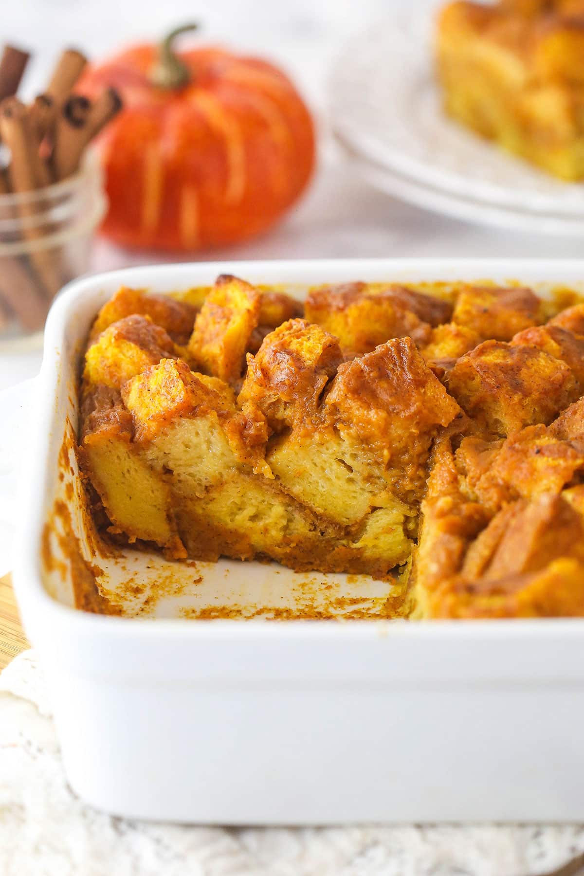 Pumpkin bread pudding in a casserole dish with a couple of slices taken from it.