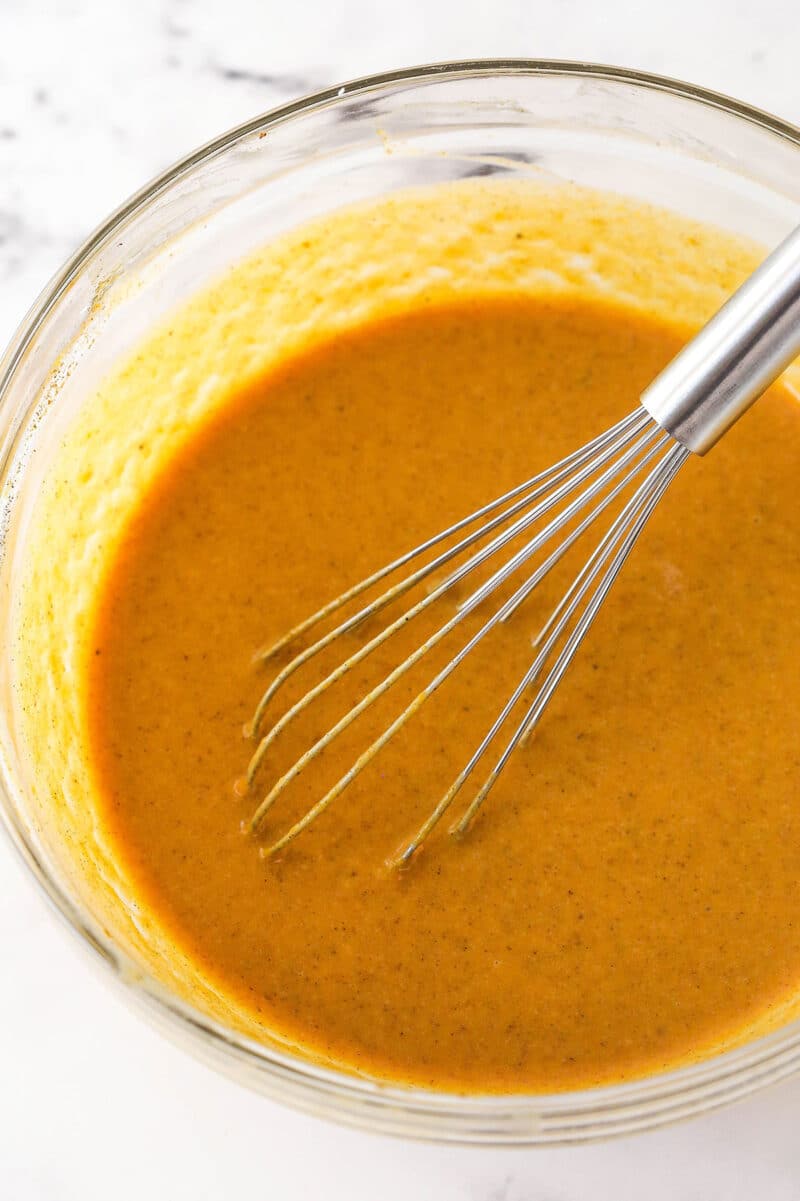 Pumpkin pie filling in a bowl with a whisk.