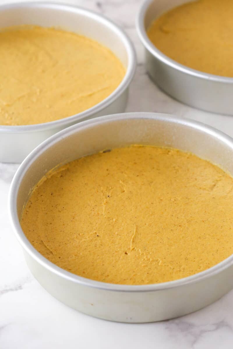 Pumpkin cake batter divided between 3 cake pans.