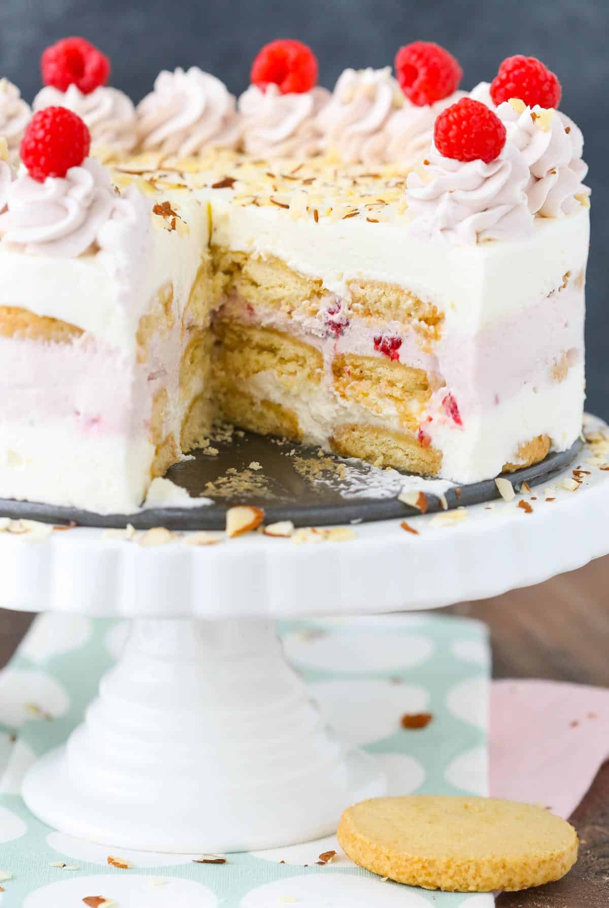 A raspberry almond shortbread icebox cake with a slice removed on a white cake stand.