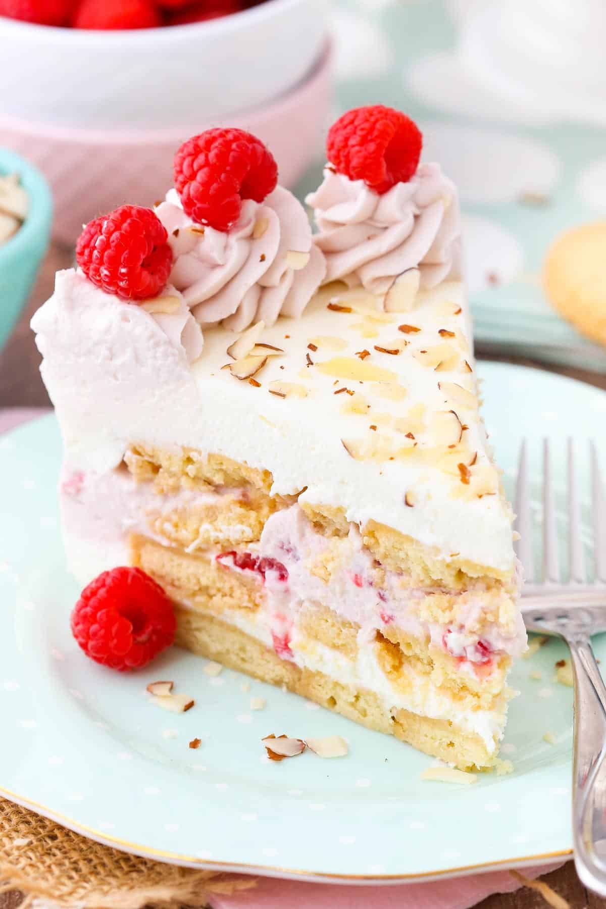 Close up of a slice of raspberry almond shortbread icebox cake on a light blue plate.