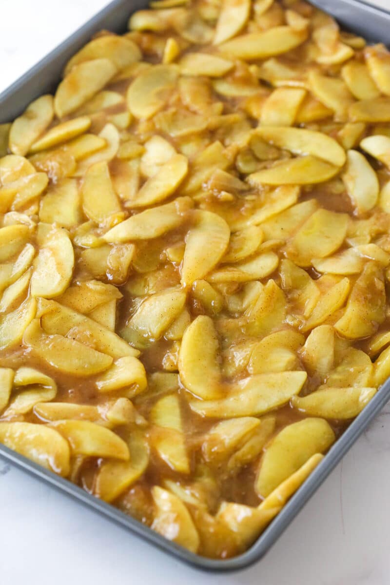 Apple filling for slab apple pie spread out in a sheet pan to cool.