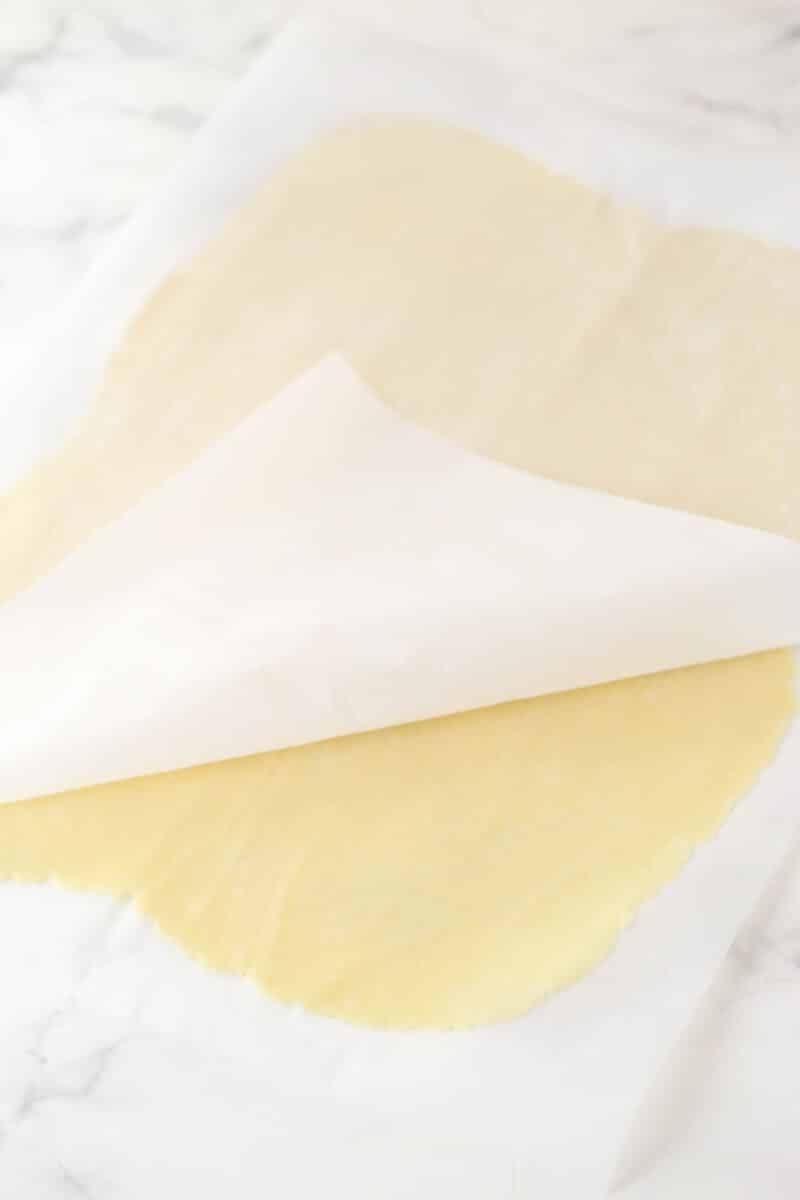 Pie dough rolled out between two pieces of parchment paper.