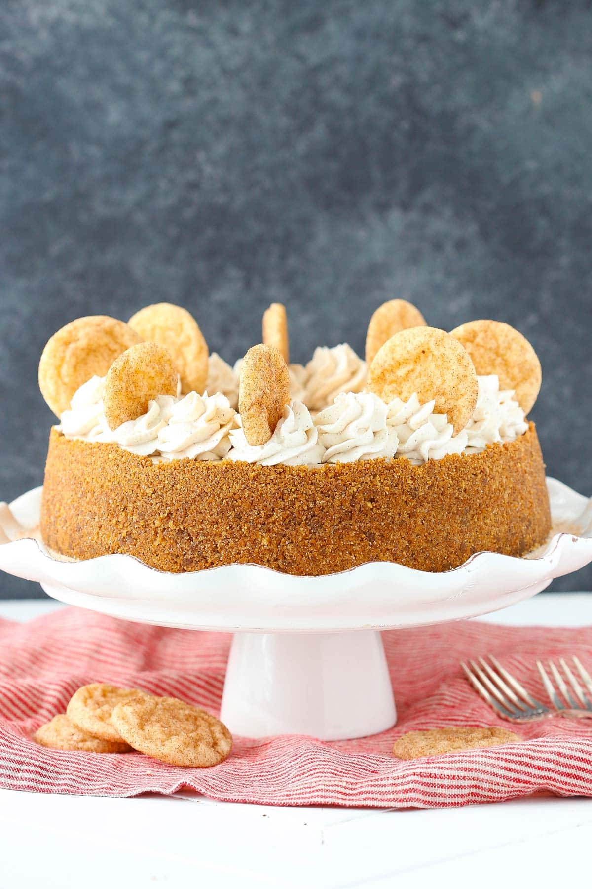 A snickerdoodle dulce de leche cheesecake on a white ruffled cake plate.