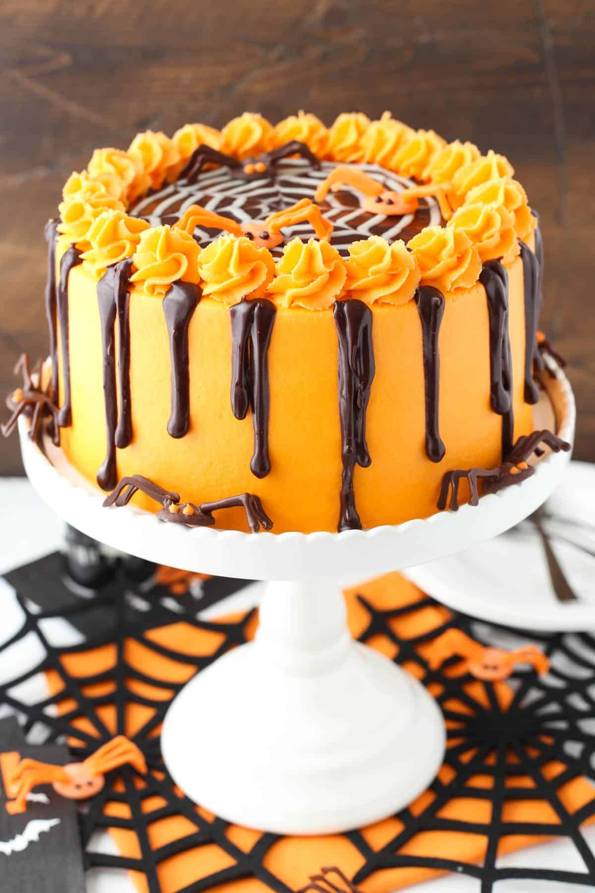 A spiderweb chocolate cake on a white cake stand.