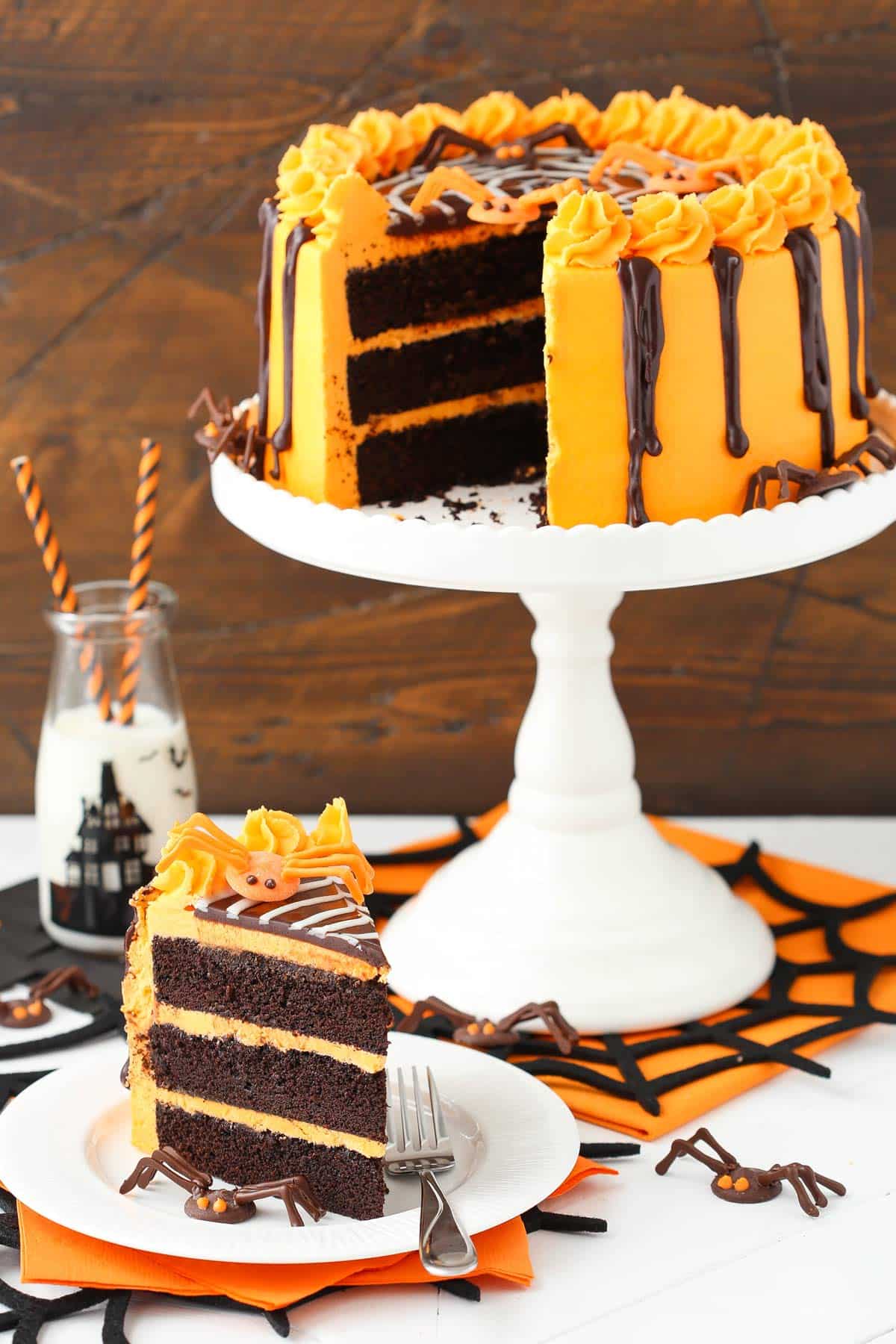 A slice of spiderweb chocolate cake on a plate with the rest of the cake in the background.