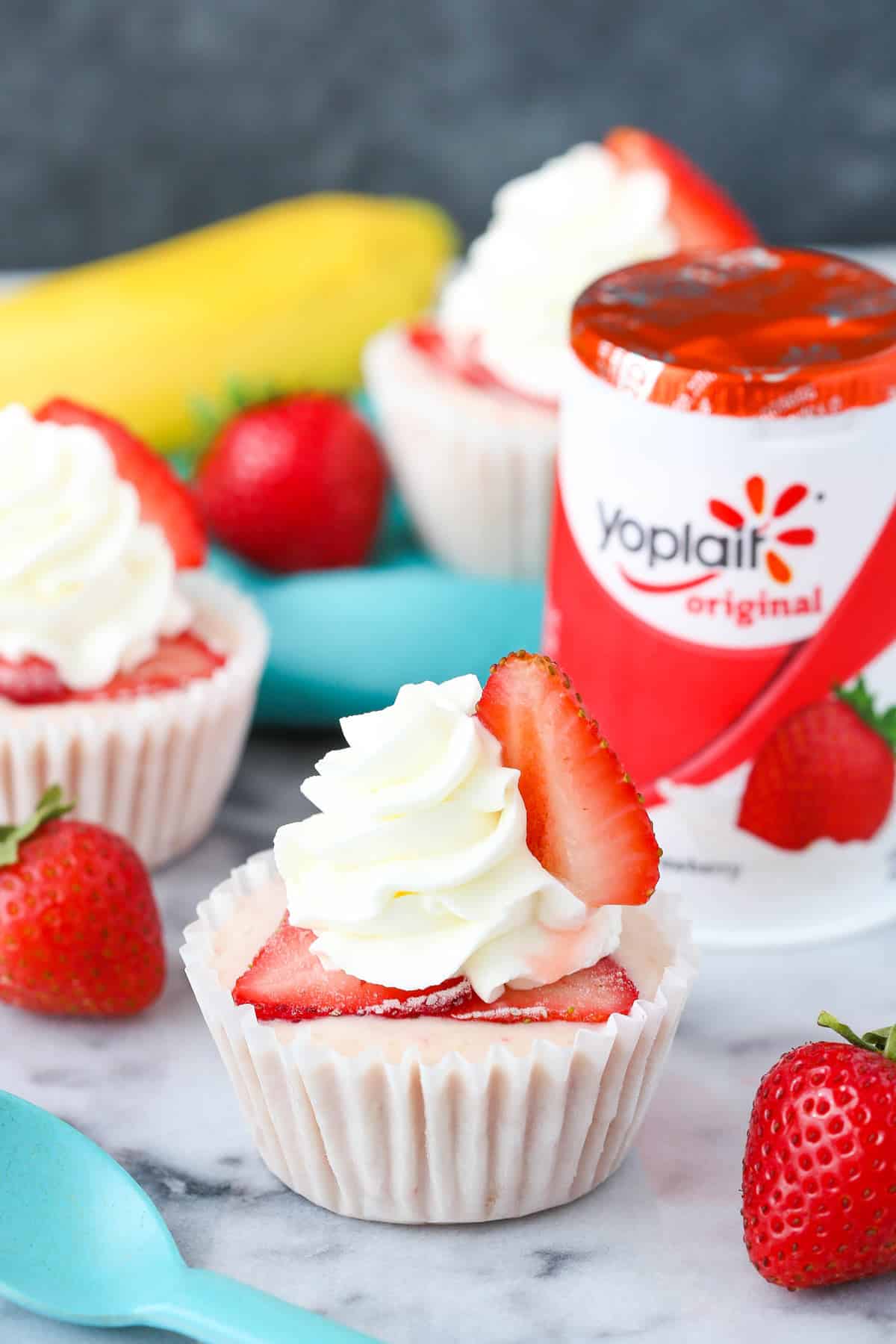 Close up of a strawberry banana frozen yogurt cupcake with yogurt in the background.