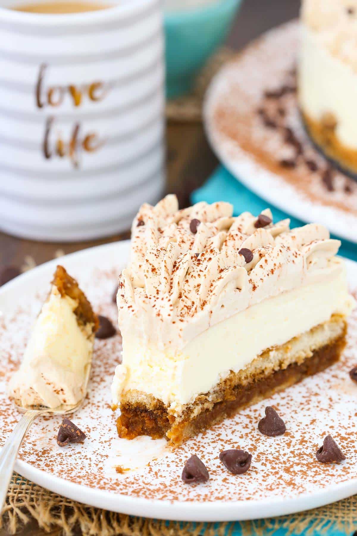 A slice of tiramisu cheesecake with a bite removed on a fork.