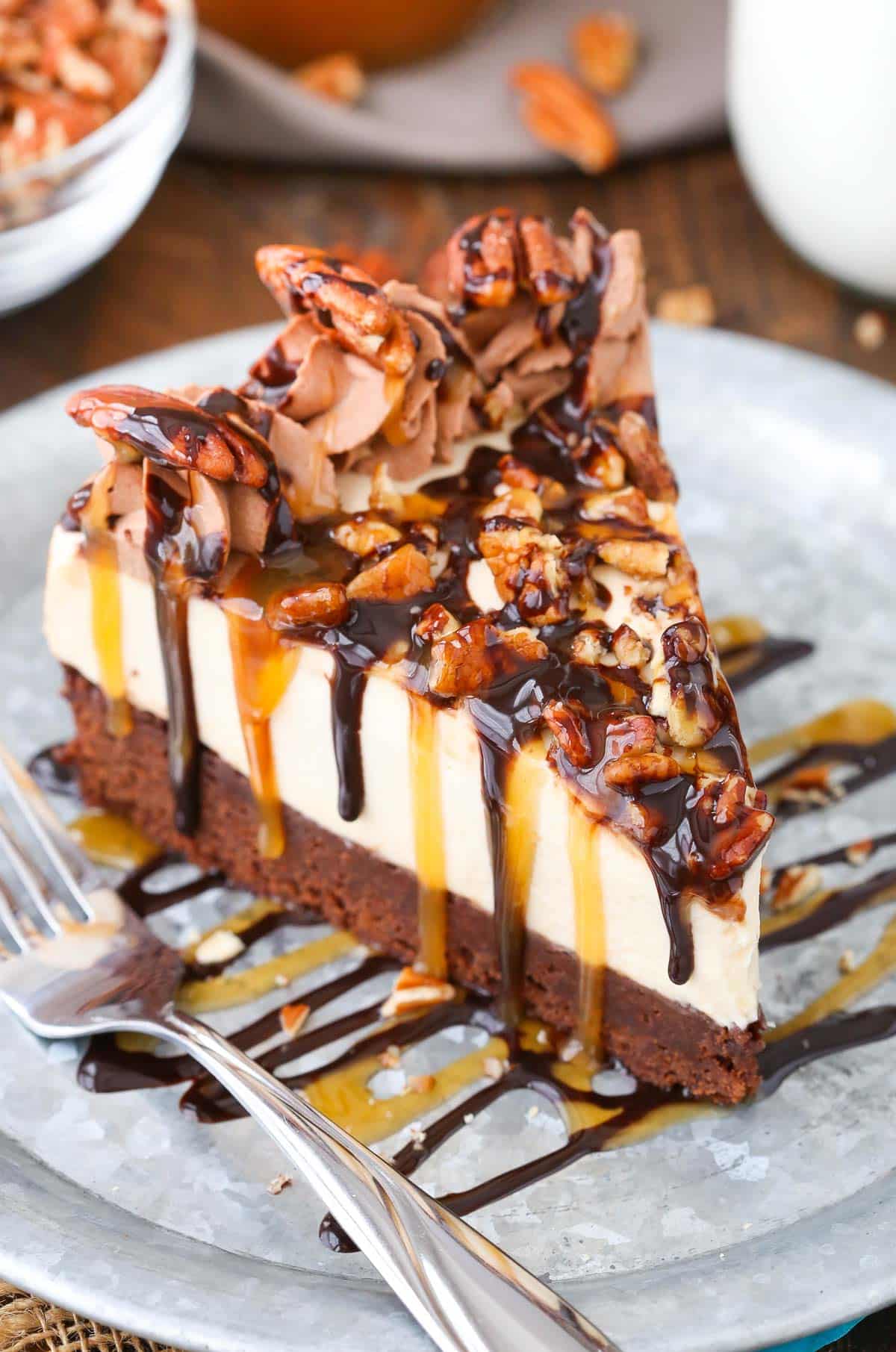 A slice of turtle brownie cheesecake on a silver plate.