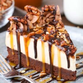 A slice of turtle brownie cheesecake on a silver plate.