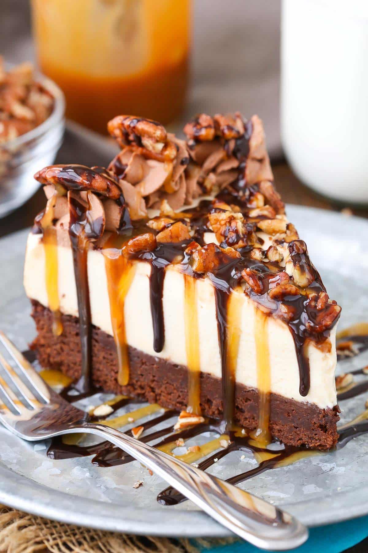 A slice of turtle brownie cheesecake on a silver plate.