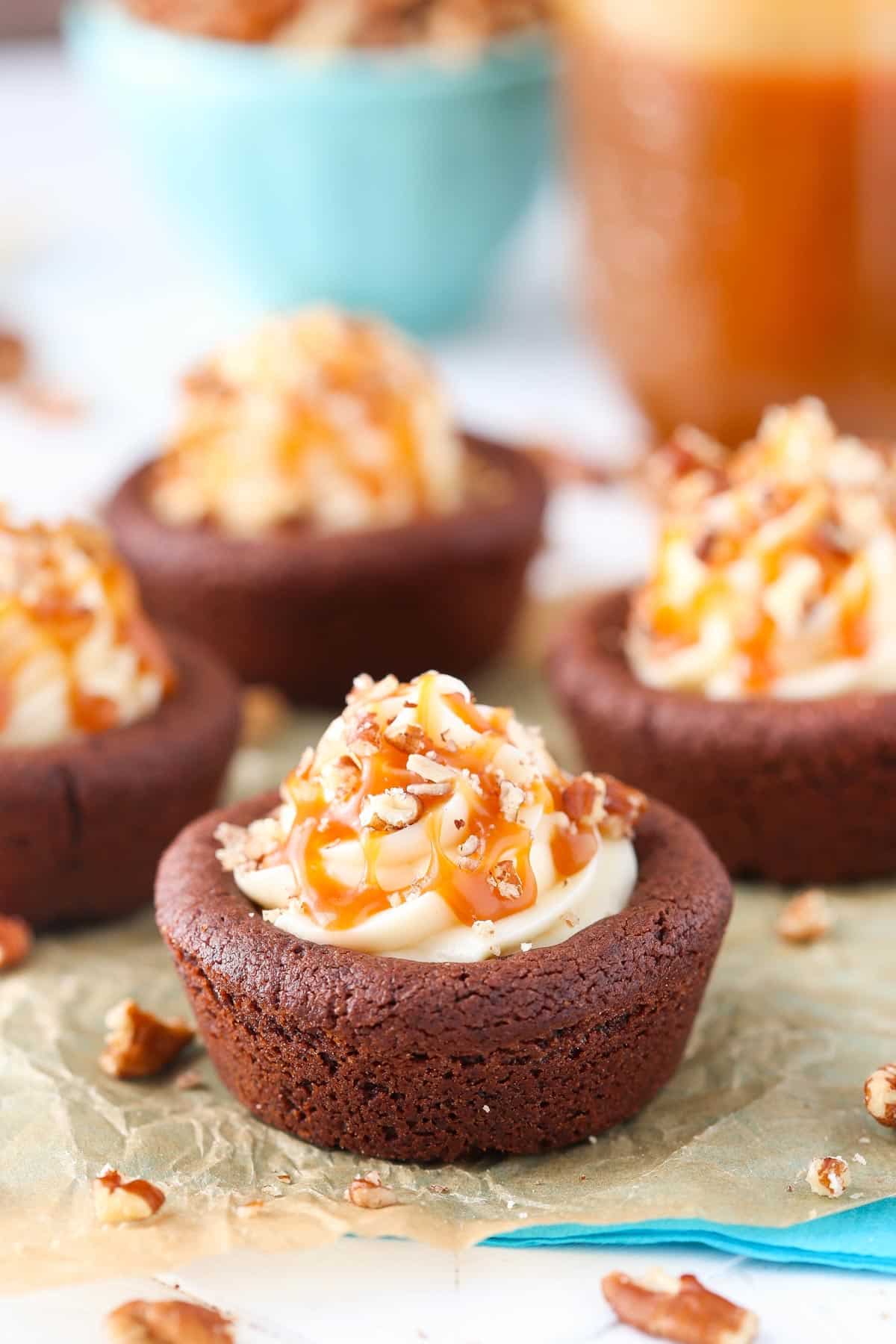 Close up of a turtle chocolate cookie cup on a piece of parchment.