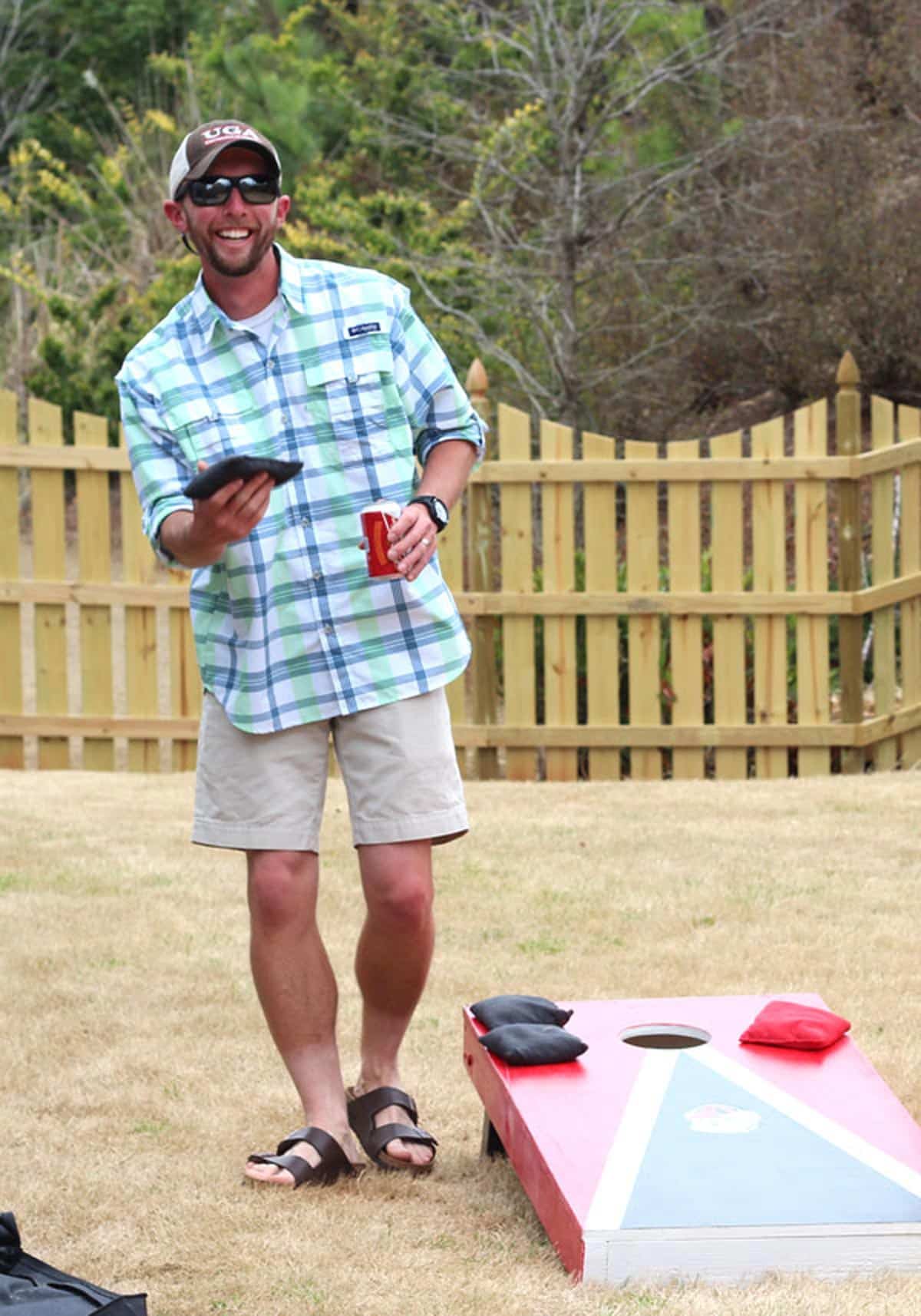 A picture of a man playing corn hole.