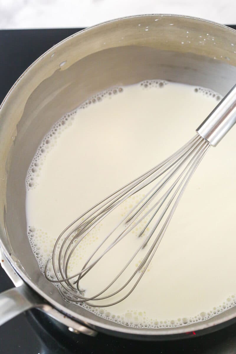 Heating a mixture of cornstarch, salt, milk, and heavy cream in a saucepan.