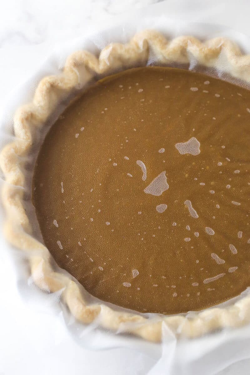 Butterscotch pie with clear wrap pressed into the filling.