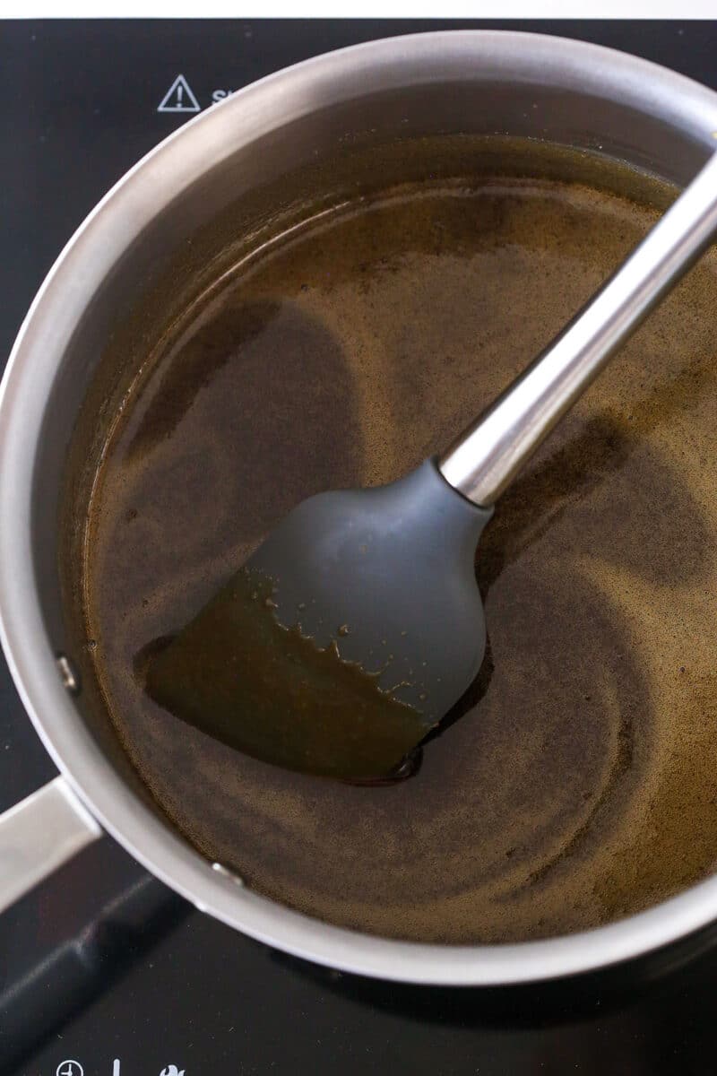 Dissolving dark brown sugar in water in a saucepan.