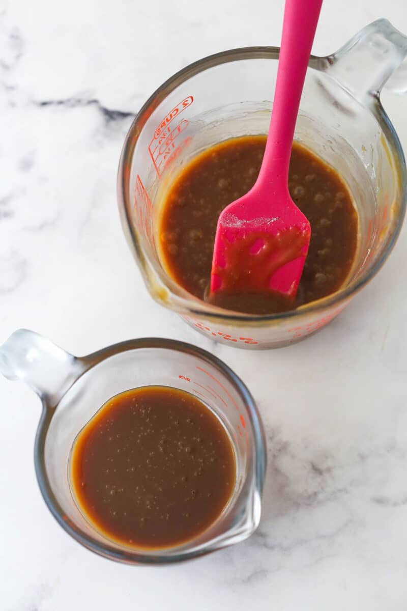 Caramel divided into two measuring cups. One has flour mixed into it. One doesn't.