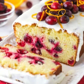 An orange cranberry loaf with a slice cut from it.