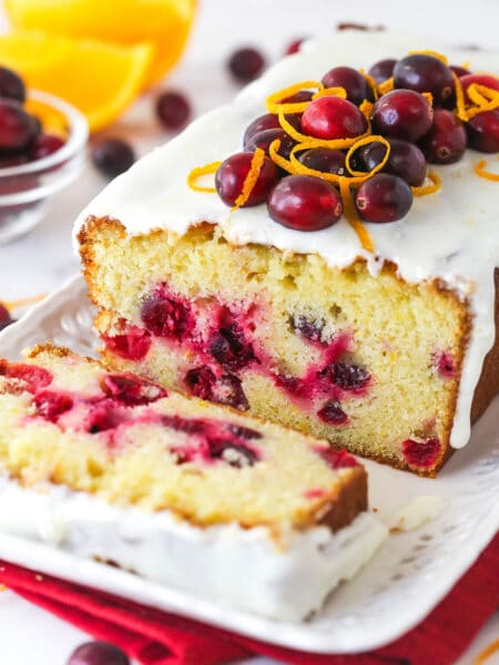 An orange cranberry loaf with a slice cut from it.