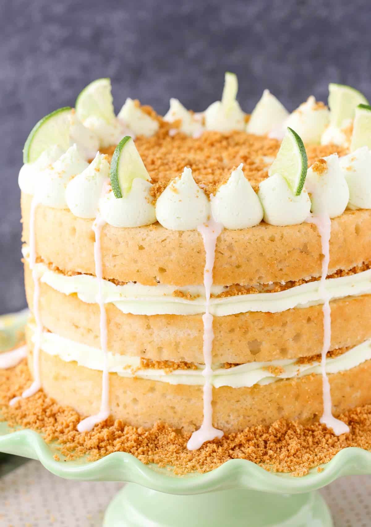 Close up of a key lime pie layer cake on a light green cake stand.