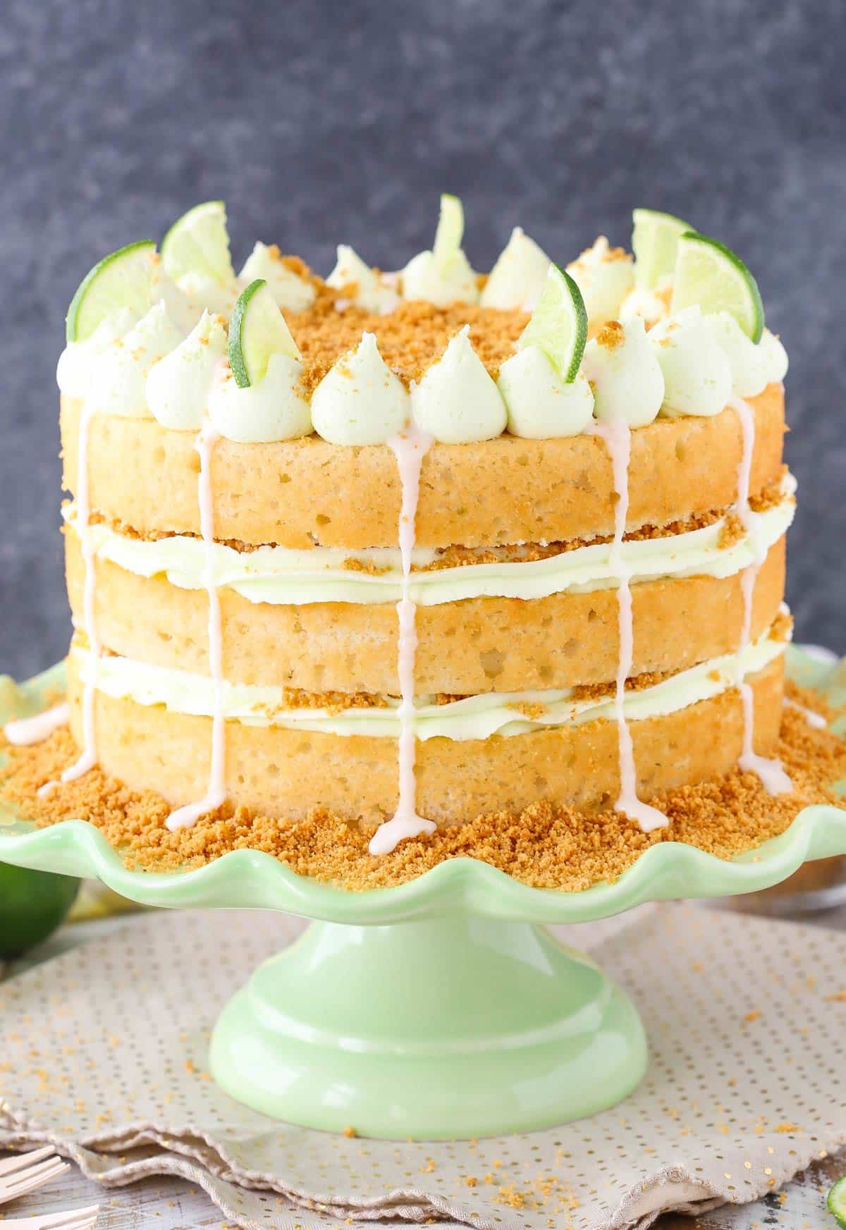 Side view of a key lime pie layer cake on a light green ruffled cake stand.