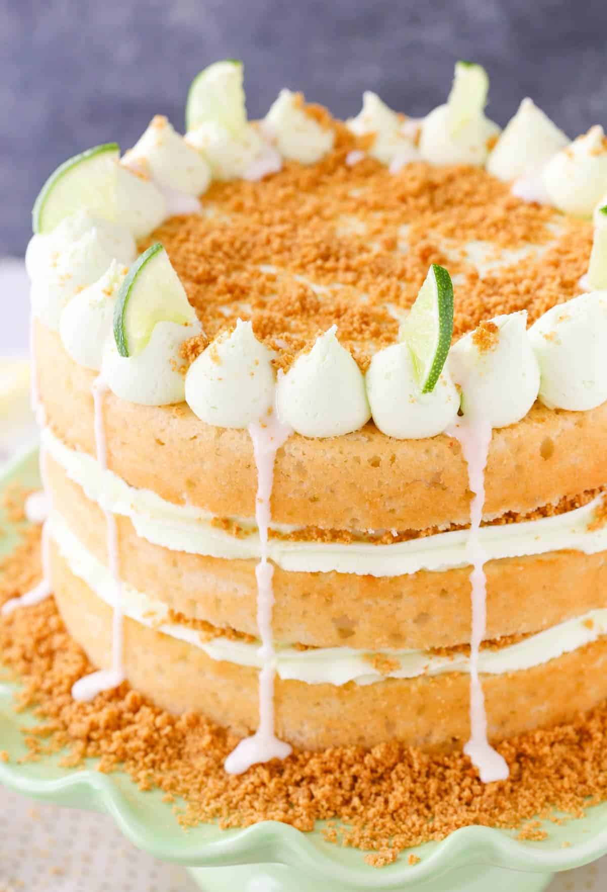 Close up of a key lime pie layer cake on a light green cake stand.