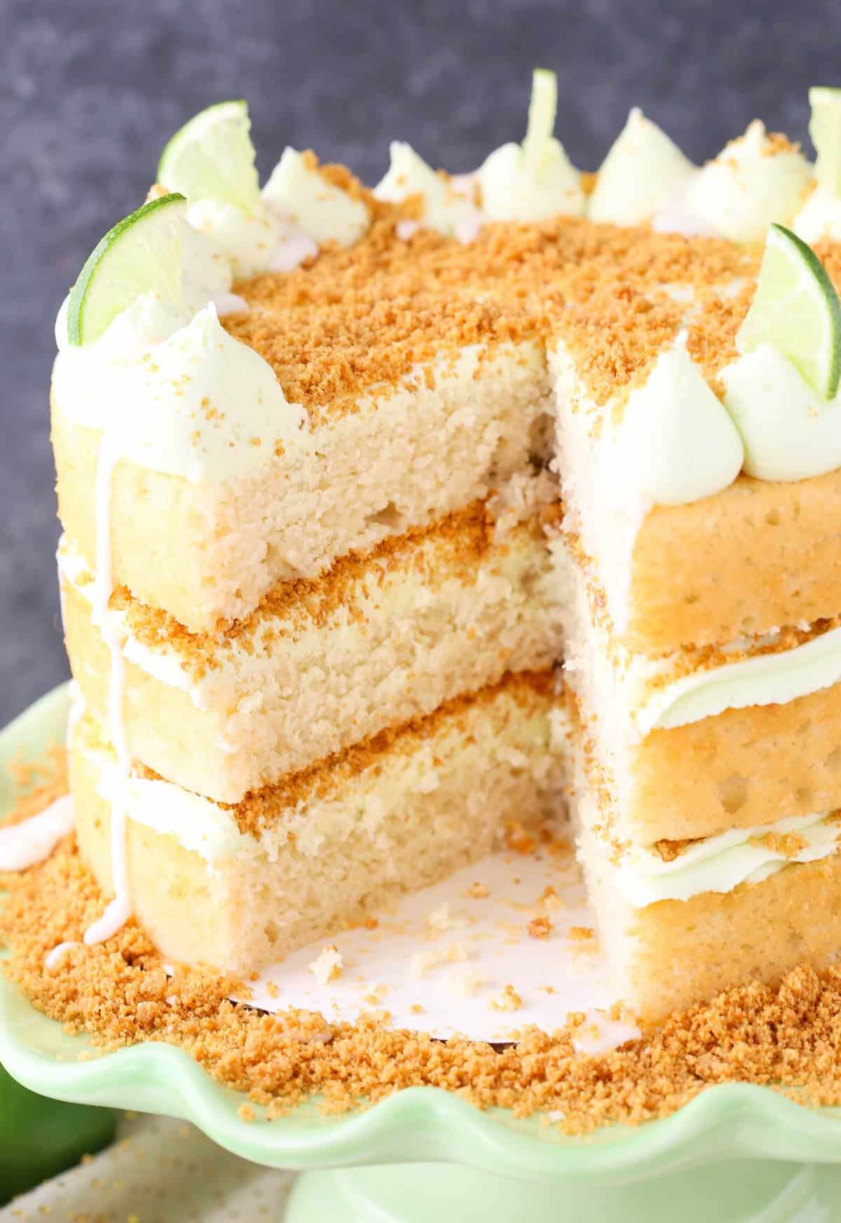 Close up of a key lime pie layer cake with a large slice removed to show inside layers.
