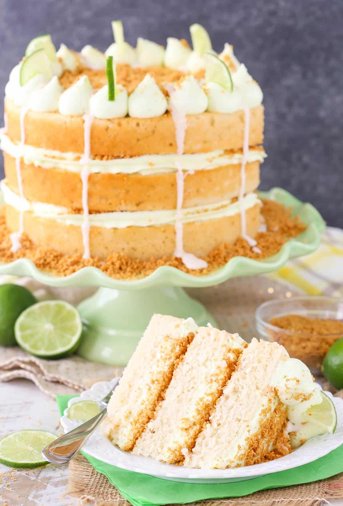 A slice of key lime pie layer cake with the rest of the cake in the background.