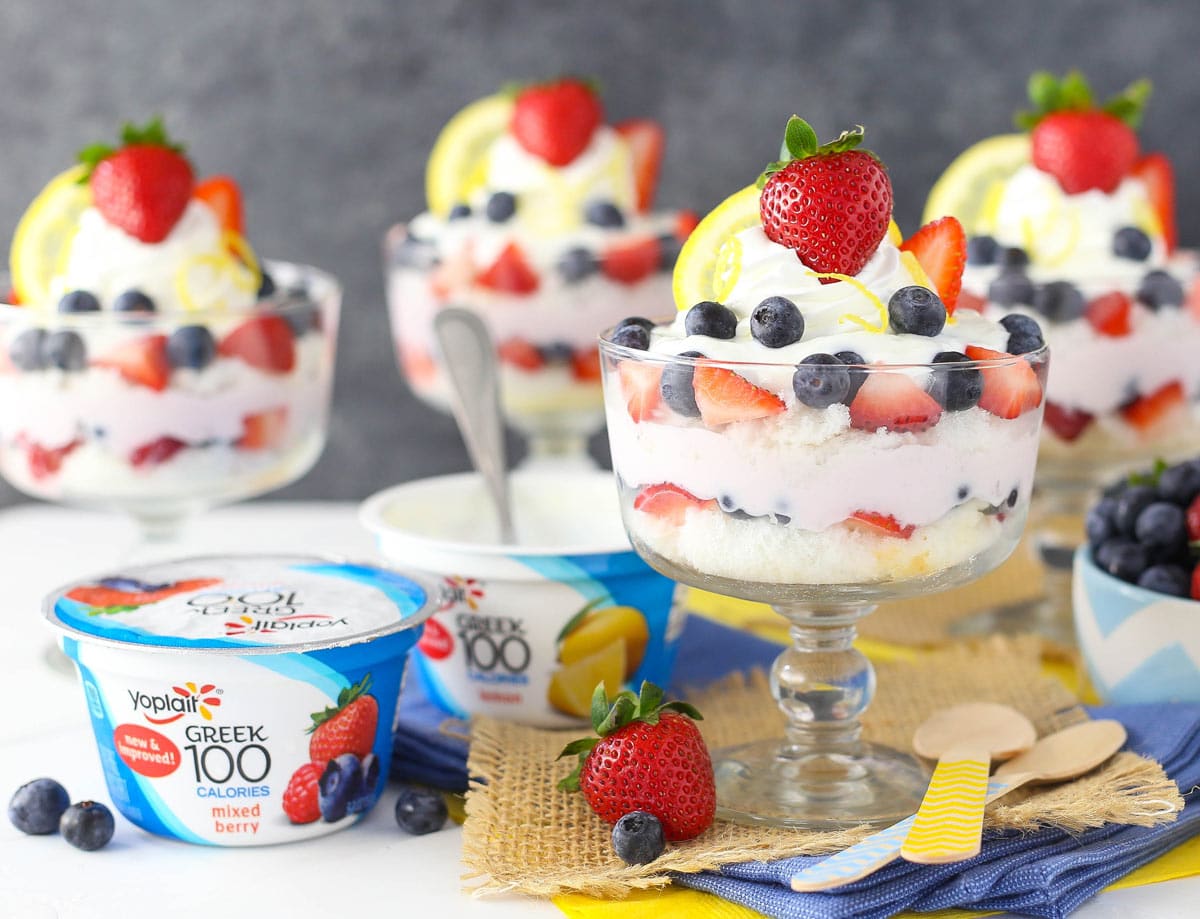 Two containers of yogurt next to a lemon berry yogurt trifle.