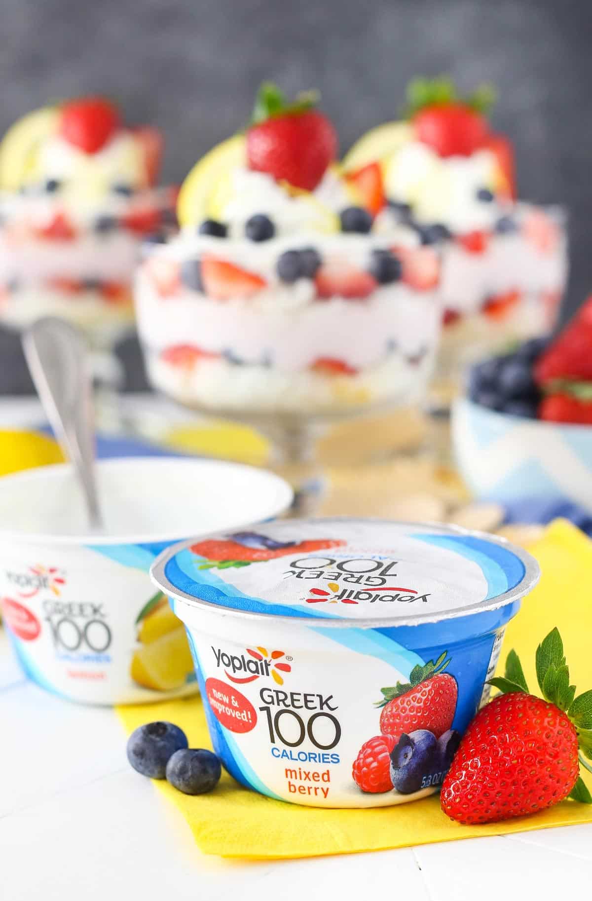 Close up of a container of yogurt with trifles in the background.