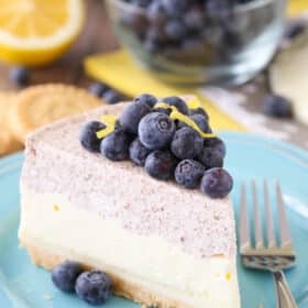 Side view of a slice of lemon blueberry shortbread mousse cake on a small blue plate.
